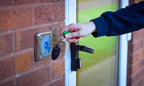 White womans hand using magnetic key fob to gain access to shared accommodation from outdoors